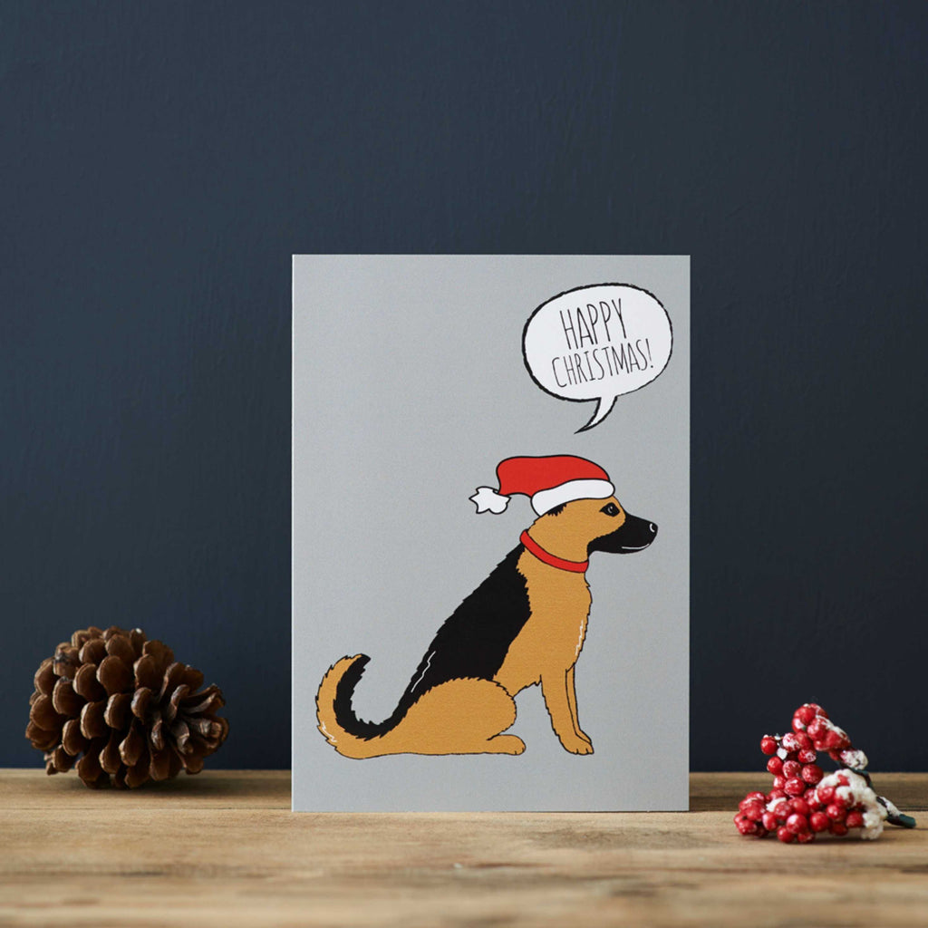 Deutscher Schäferhund Weihnachtskarte. Hund mit Weihnachtsmütze auf grauem Hintergrund